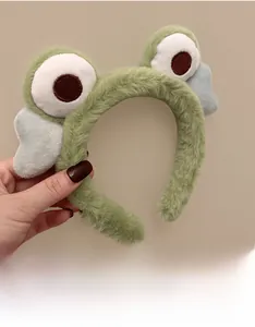 Detailed view of plush green frog headband with cute big eyes for washing face