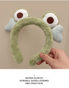 Detail of green plush headband showing super elastic texture and cute cartoon frog eyes