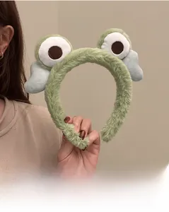 Detail shot of cute green plush headband with large eyes and wings, soft coral fleece texture