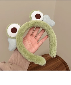 Close-up of fuzzy green plush headband featuring large cute cartoon eyes and soft texture