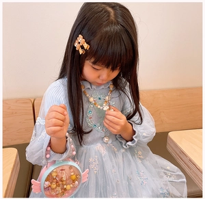 Close-up of kids cartoon bear hair clip and round beaded necklace with mini wings bag