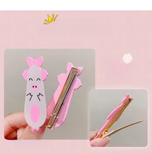 Detail of pink 3D cartoon pig hair clip with glitter finish and golden metal duckbill base