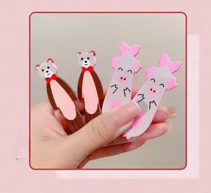 Detailed view of four cute cartoon pig and bear hair clips held in hand for size