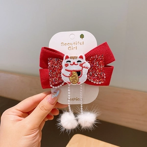 Détail d'un nœud papillon rouge avec broderie chat porte-bonheur, paillettes et pompons