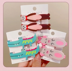 Detail view of cute cartoon animal hair clips featuring bears, crocodiles, and little pigs