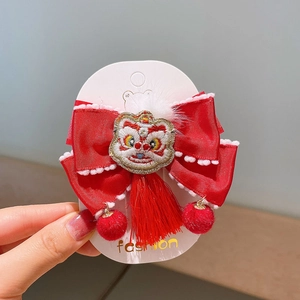 Détail de la pince à cheveux Nouvel An avec broderie lion et pompons rouges festifs