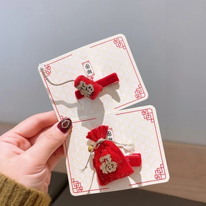 Détail de barrettes en velours rouge avec broderie dorée, glands et cloches pour filles