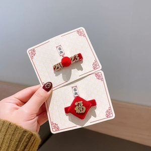 Détail de barrettes de Nouvel An avec caractère Fu doré et pompons en vison