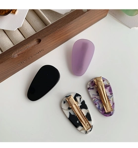 Set of four teardrop hair clips in black and marble patterns on a white tabletop