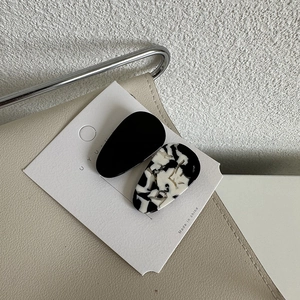 Close-up of sleek acetate water-drop hair clips in solid black and marble patterns