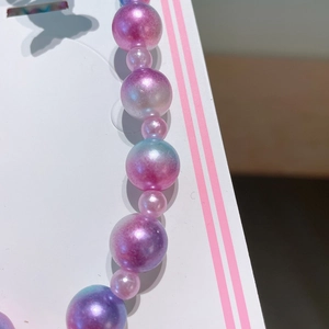 Detail shot of pearlescent gradient beads in pink purple and blue on the necklace set