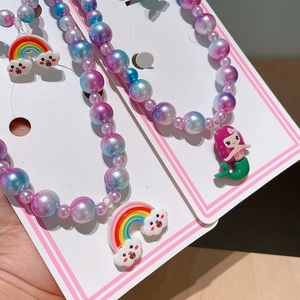 Detail of girls' mermaid necklace with iridescent beads and colorful rainbow pendant