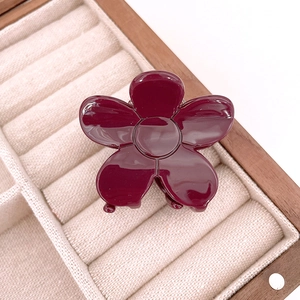 Macro shot of a glossy deep red acetate flower hair claw clip in a velvet jewelry box