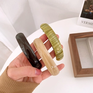 Detail view of handmade rectangular acetate hair clips in black, beige and green colors