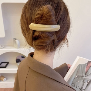 Detail of elegant beige marble hair clip on a low ponytail with a smooth acetate finish
