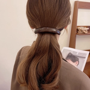 French style brown acetate hair clip shown in a back view securing a low ponytail hairstyle