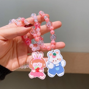 Detail of beaded jewelry with cute cartoon girl and bear charms held by a hand