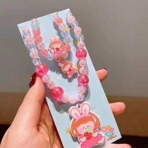 Close-up of pink beaded children's jewelry set featuring a cute cartoon girl pendant