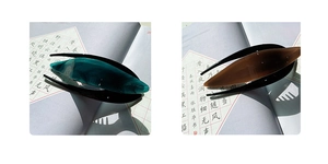 Detail of amber and teal acetate hair clips with sleek leaf shape and glossy finish