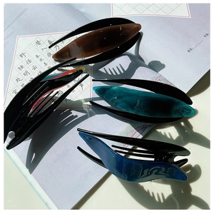 Detailed view of four colorful acetate hair clips with sleek glossy finish on paper