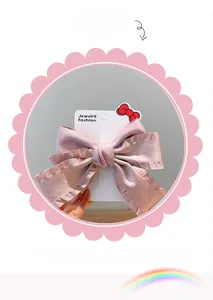 Detail showing pink ruffled bow hair clip with silk texture on display card