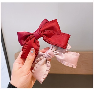 Detailed view of handmade pleated satin bow hair clips in vintage red and soft pink