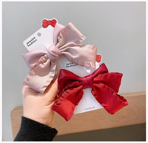 Detail of handmade satin bow hair clips in dark red and dusty pink on display cards