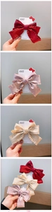 Detail of multi-color ruffled fabric bow hair clips in red, pink, and beige on cards