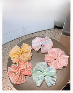 Détail de cinq barrettes à nœuds en mousseline fleurie de couleurs variées
