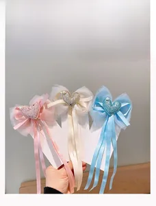 Dettaglio di fermagli per capelli in pizzo con cuori glitterati e perle in tre colori pastello