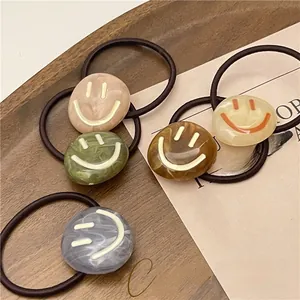 Set of five elastic hair ties with marble pattern smiley face acrylic charms on wood