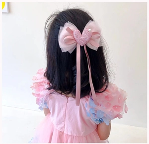 Dettaglio del fermaglio per capelli con fiocco di pizzo rosa, paillettes e cuore