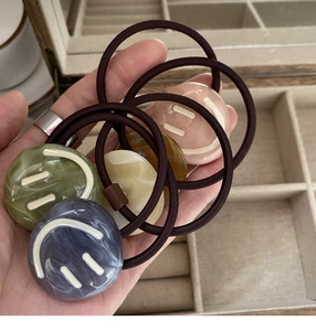 Detail of colorful resin smiley face hair ties set in a velvet jewelry box display