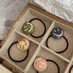 Set of four elastic hair ties with marble pattern resin charms and smiley face designs