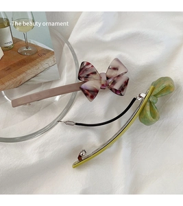 Detail view of two acetate bow hair clips with elegant marble textures and spring mechanism