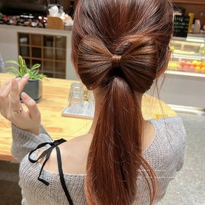 Dettaglio del fermaglio per chignon a fiocco marrone caramello su una coda di cavallo