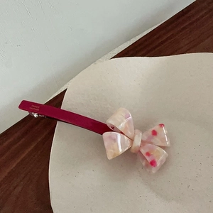 Detailed macro of a beige bow hair clip with red spots and France Handmade engraving