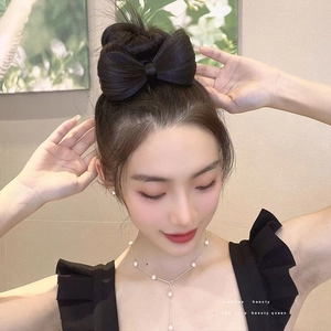 Dettaglio della consistenza dei capelli sintetici e del design a fiocco nero della clip per capelli