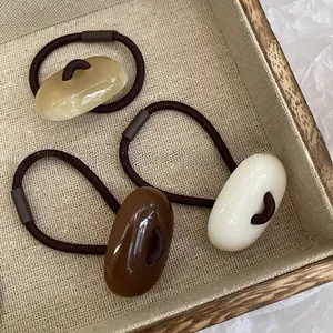 Close-up of minimalist earth-tone acrylic stone hair ties in a wooden tray