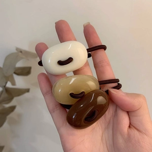 Three-piece set of acrylic donut hair ties in cream, camel, and brown for high pony styles
