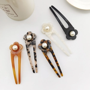 Detailed close-up of U-shaped hair pins with floral pearl accents in diverse patterns