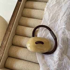 Detailed macro view of an oval resin charm on a high-elastic brown ponytail holder