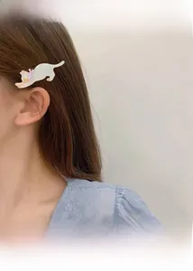 Detailed close-up of a white acetate cat hair clip with a pink bow worn by a model