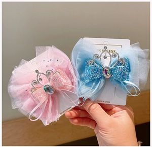 Dettaglio del fermaglio a fiocco con glitter, rete di tulle e corona per bambina