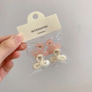 Nahaufnahme von vier Blumen-Haarklammern in Pink und Beige, verpackt als Mini-Set
