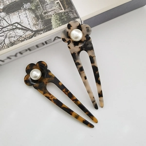 Detail view of acetate U-shaped hair pins with elegant floral pearls and leopard pattern