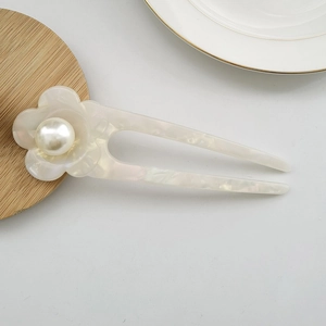 Detail of elegant white floral acetate hair pin with pearl center for bun styling