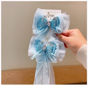 Dettaglio di fermagli per capelli in tulle azzurro con fiocchi di paillettes e corone argentate