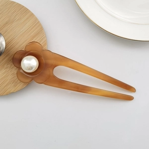 Macro detail of tortoiseshell acetate flower hair pin with a lustrous white pearl center