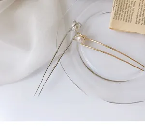 Detail of elegant gold and silver U-shaped hairpins with pearls on a vintage background